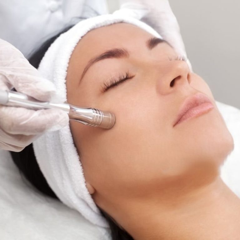 The cosmetologist makes the procedure Microdermabrasion of the facial skin of a beautiful, young woman in a beauty salon.Cosmetology and professional skin care.